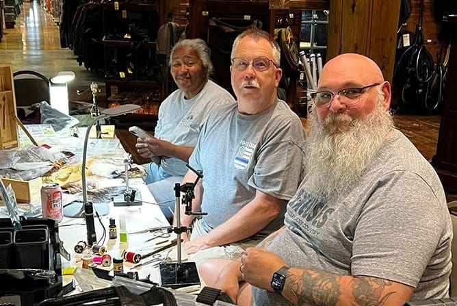 Three men sitting at a table with some tattoos on their arms.
